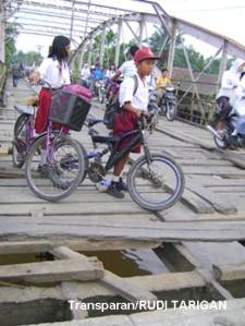 Dua murid SD turun dari sepedanya saat akan melalui Jembatan Patimura / Jembatan Teluk Bakung Milik Propinsi Sumatera Utara, yang berada di Kecamatan Tanjung Pura Kabupaten Langkat, Senin 3 Agustus 2009. yang mengalami kerusakan parah. (RUDI TARIGAN)